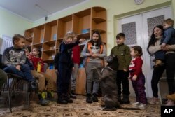 Children traumatized by the war play with an American Pit Bull Terrier "Bice" in the Center for Social and Psychological Rehabilitation in Boyarka close Kyiv, Ukraine, Wednesday, Dec. 7, 2022. (AP Photo/Vasilisa Stepanenko)