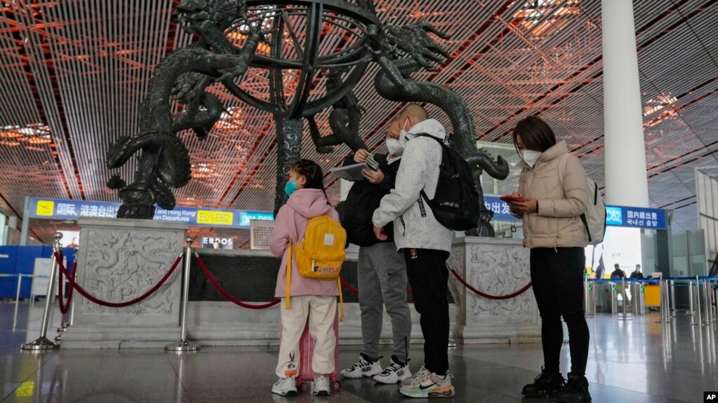 2022年12月29家庭成员在北京首都国际机场国际登机口前检查护照(photo:VOA)