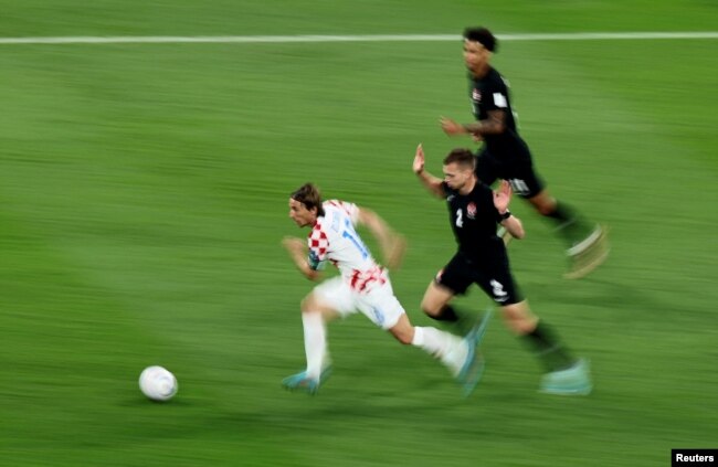 El croata Luka Modric en acción con el canadiense Alistair Johnston.