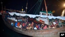 Para pengungsi Rohingya duduk di atas kapal kayu ketika kapal tersebut tiba pelabuhan Krueng Geukueh, Aceh Utara, pada 30 Desember 2021. (Foto: AP/Rahmat Mirza)