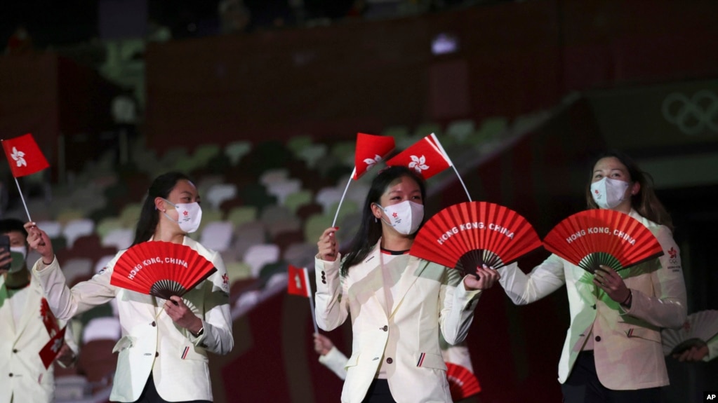 资料照 - 2021年在东京举行的2020东京夏季奥运会开幕式上，香港代表队队员手举香港区旗和印有“香港·中国”英文字的红色扇子走进场内。(photo:VOA)