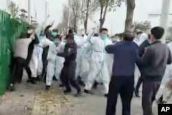 中國河南鄭州富士康代工廠裡身穿防護服的警察和保安毆打參加示威活動的工人。 (2022年11月23日)