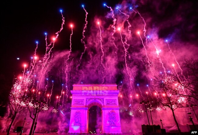 Los fuegos artificiales estallan junto al Arco del Triunfo celebrando la llegada del 2023, que se ve proyectado en el edificio, en la Avenue des Champs-Elysees durante las celebraciones de Año Nuevo en París, la madrugada del 1 de enero de 2023. [AFP]