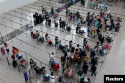 FILE - Travelers queue up for shuttle bus to quarantine hotels at the Hong Kong International Airport, amid the COVID-19 pandemic, in Hong Kong, Aug. 1, 2022.