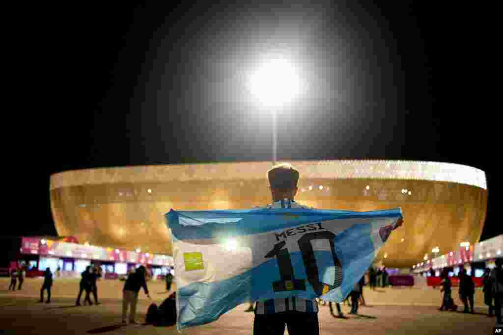 A man holds an Argentinian flag ahead of the World Cup quarterfinal soccer match between the Netherlands and Argentina, outside the Lusail Stadium in Lusail, Qatar.