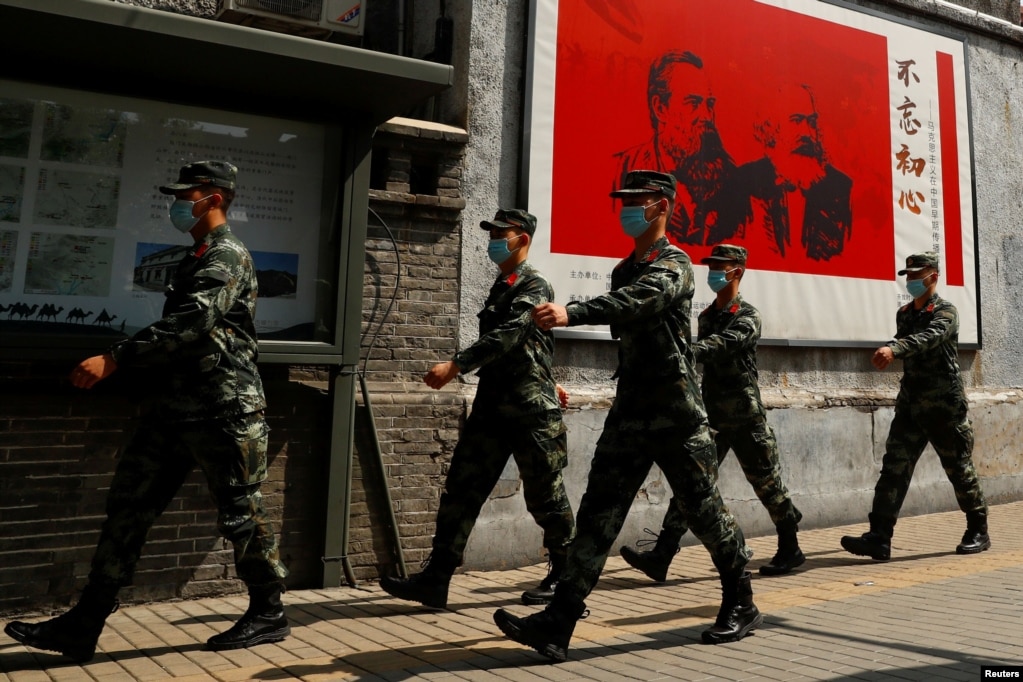 资料照：中国武警士兵走过北京街头一幅马克思恩格斯画像及写有“不忘初心”的宣传画。（2020年5月22日）(photo:VOA)