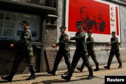 资料照：中国武警士兵走过北京街头一幅马克思恩格斯画像及写有“不忘初心”的宣传画。（2020年5月22日）