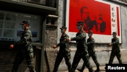 资料照：中国武警士兵走过北京街头一幅马克思恩格斯画像及写有“不忘初心”的宣传画。（2020年5月22日）