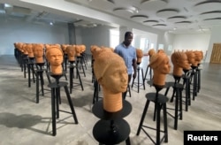 A man walks across a set up of terra cotta heads, a French woman collection representing the remaining Chibok school girls in captivity in Lagos, Nigeria, November 29, 2022. (REUTERS/Seun Sanni)