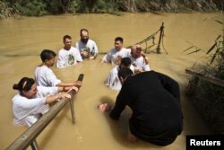 FILE - Christian pilgrims dip in the water at the baptismal site known as Qasr el-Yahud on the banks of the Jordan River near the West Bank city of Jericho, May 21, 2014.