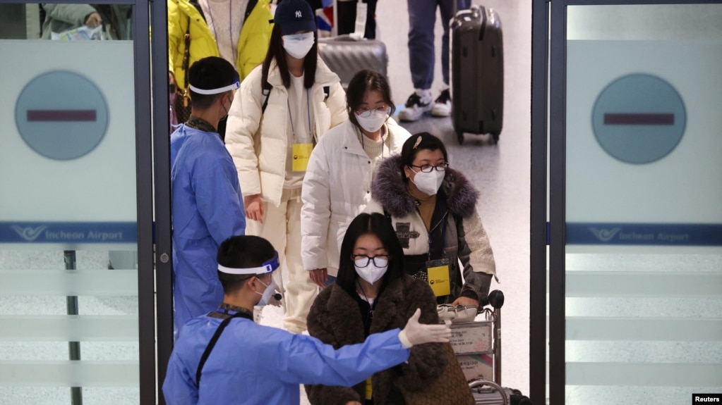 身穿防护服的韩国军人指引从中国抵达仁川国际机场的乘客进行新冠核酸检测。（2023年1月4日）(photo:VOA)