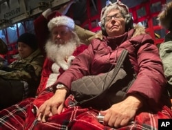 Santa and Mrs Claus rest on the plane trip to Nuiqsut, Alaska, Nov. 29, 2022.