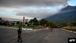A traffic safety officer stands next to a closed-off road after the Fuego volcano erupted, in Alotenango, some 65 kilometers southwest of Guatemala City, Guatemala, Dec. 11, 2022.