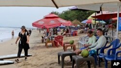 Turis menikmati suasana pantai di Bali, Sabtu, 12 November 2022. (AP/Firdia Lisnawati)