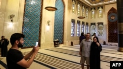 Pasangan asal Kanada Dorinel dan Clara Popa berpose di dalam Masjid Biru atau Blue Mosque, di Doha, pada 29 November 2022, ketika berkunjung ke Qatar untuk menyaksikan Piala Dunia 2022. (Foto: AFP/Mahmud Hams)