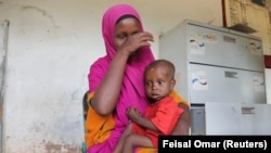 A displaced woman holds her one year old malnourished child at a hospital in Somalia.