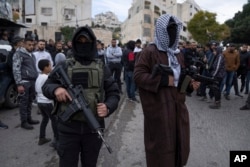 Dua pria bersenjata Palestina menjaga keamanan saat pemakaman Ahmed Abu Junaid (21 tahun), di kamp pengungsi Tepi Barat Balata, Nablus, Kamis, 12 Januari 2023. (AP/Nasser Nasser)