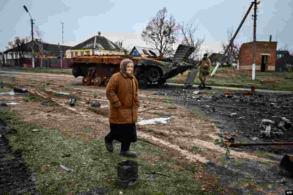 A woman walks past a destroyed armored personal carrier in the liberated village of Petropavlivka near Kupiansk, Kharkiv area, amid the Russian invasion of Ukraine.