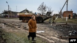 A woman walks past a destroyed armored personal carrier in the liberated village of Petropavlivka near Kupiansk, Kharkiv area, amid the Russian invasion of Ukraine.