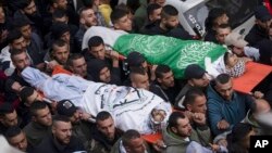 Mourners carry the bodies of Samer Houshiyeh, 21, left, and Fouad Abed, 25, during their funeral in the West Bank city of Jenin, Jan. 2, 2023.