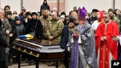 Catholic priests pray at a coffin of Denis Tarasov, a Ukrainian volunteer soldier and a well-known lawyer, killed in a battlefield in the Donetsk region, during farewell ceremony in Zaporizhzhya, Ukraine, Jan. 13, 2023.