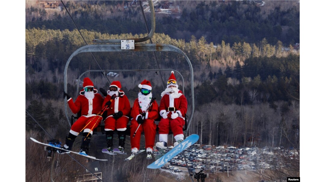 Para pemain ski berpakaian Sinterklas menaiki lift untuk berpartisipasi dalam acara amal di resor ski Sunday River di Bethel, Maine, AS, 5 Desember 2021. REUTERS/Brian Snyder