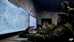 Ukrainian soldiers watch drone feeds from an underground command center in Bakhmut, Donetsk region, Ukraine, Sunday, Dec. 25, 2022. (AP Photo/Libkos)