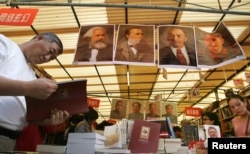 资料照：一名男子在书市里走过国际共产主义运动的领导人马克思、恩格斯、列宁和斯大林的画像。