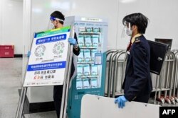 Staf stasiun kereta bawah tanah di Guangzhou di provinsi Guangdong selatan China, melepas poster kode kesehatan COVID-19 menyusul pelonggaran pembatasan COVID-19 di kota tersebut, 7 Desember 2022. (Foto oleh CNS / AFP) / China OUT