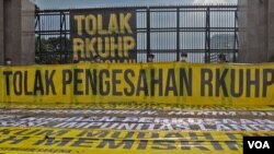 Sejumlah atribut spanduk dan poster terbentang di depan Gedung DPR pada Senin (5/12) siang yang isinya menolak pemerintah untuk mengesahkan RKUHP. (Foto: VOA/Indra Yoga) 