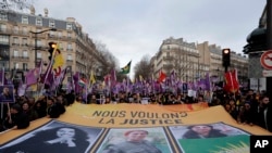 Para aktivis membentangkan spanduk bertuliskan "Kami menuntut keadilan" dalam kasus pembunuhan tiga aktivis Kurdi pada 2013, dalam demo di Paris, Sabtu, 7 Januari 2023. (Foto: ( AP Photo/Lewis Joly)