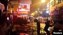 Demonstrators protesting over coronavirus disease (COVID-19) restrictions throw glass bottles towards riot police in Guangzhou, Guangdong province, China in this screen grab taken from a social media video released November 30, 2022