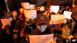 FILE - Protesters hold up blank papers and chant slogans as they march in protest in Beijing, Nov. 27, 2022. In a society where everything is closely monitored and censored, the white paper is a silent protest against users not being allowed to speak. 