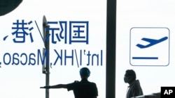 2022年8月24日，北京機場一名機場安保指示一位戴口罩的旅客繼續前往安檢口進行安檢。