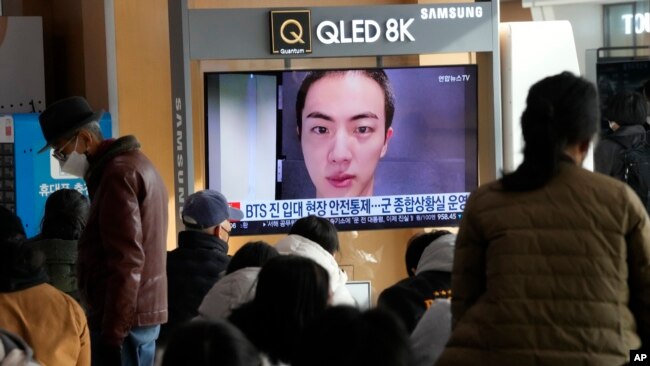 A TV screen shows an image of BTS's member Jin with a shaved head, at the Seoul Railway Station in Seoul, South Korea, Monday, Dec. 12, 2022. South Korean media report that Jin is enlisting in the military service on Tuesday. (AP Photo/Ahn Young-joon)