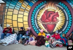 Migrants try to stay warm while camping outside the Sacred Heart Church in El Paso, Texas, on Sunday, Dec. 18, 2022. (AP Photo/Andres Leighton)