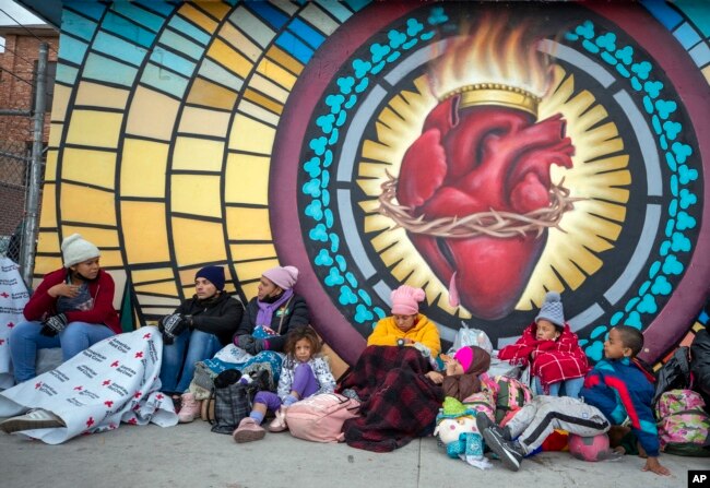 Migrants try to stay warm while camping outside the Sacred Heart Church in El Paso, Texas, on Sunday, Dec. 18, 2022. (AP Photo/Andres Leighton)