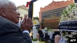 FILE - Chhang Song, former information minister, prays in front of a memorial to dozens of foreign and local journalists killed covering the country's 1970-75 war that was won by the communist Khmer Rouge regime in Phnom Penh, Cambodia, February 6, 2013.