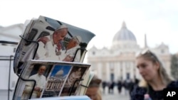 People look postcards showing Pope Francis and Pope Emeritus Benedict XVI in Rome, near the Vatican, Dec. 28, 2022. 