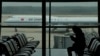 FILE - A passenger checks her phone as an Air China passenger jet taxis past at Beijing Capital International Airport, in Beijing, Oct. 29, 2022. 