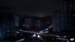 Cars drive past residential blocks which were de-energized after a Russian rocket attack in Kyiv, Ukraine, Nov. 23, 2022.