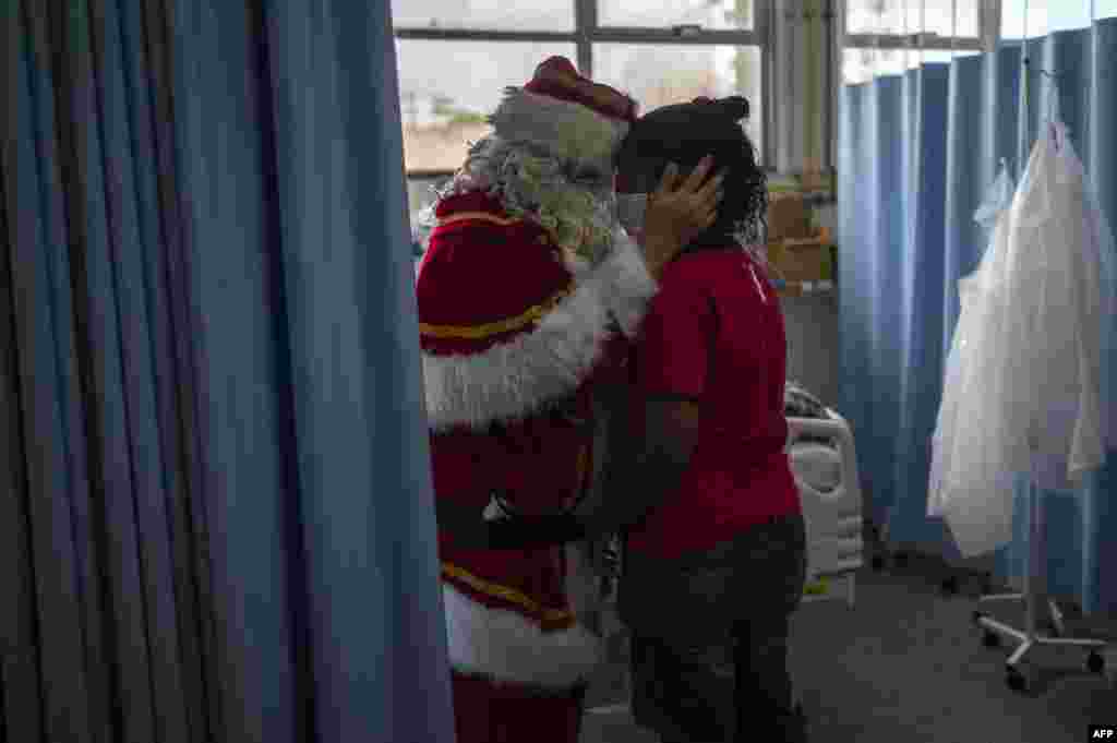 Ari Queiroz, 59, a health department worker who has dressed as Santa Claus for 20 years, hugs a mother of a patient of the ICU Pediatric ward of the Souza Aguiar Municipal Hospital in Rio de Janeiro, Brazil, on Dec. 22, 2022.