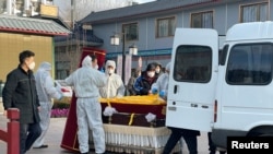 北京一家火葬場工作人員將靈柩移下車。（2022年12月17日）