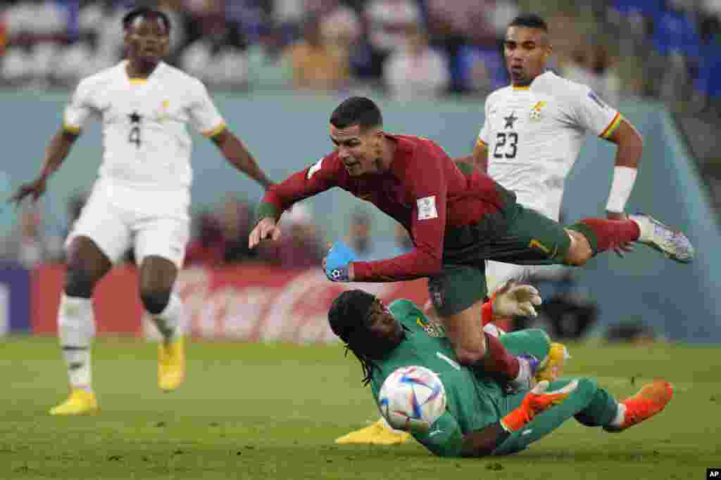 Portugal&#39;s Cristiano Ronaldo falls over Ghana&#39;s goalkeeper Lawrence Ati-Zigi during the World Cup group H soccer match between Portugal and Ghana, at the Stadium 974 in Doha, Qatar.