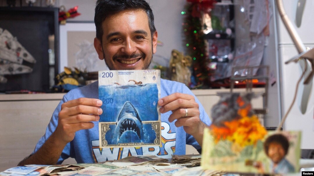 Artist Sergio Diaz holds intervened Argentine pesos bills and a US dollar depicting Steven Spielberg's movie "Shark" as a parody of Argentina's ever-increasing inflation, in Salta, Argentina, December 30, 2022. (REUTERS/Javier Corbalan)