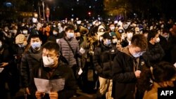 Para pengunjuk rasa berbaris di sepanjang jalan untuk berunjuk rasa terhadap pembatasan COVID-19 yang ketat di China di Beijing pada 28 November 2022. (Foto: AFP)