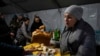 A volunteer gives free meal to people who lost electrical power after recent Russian rocket attack in a heating point in the town of Vyshhorod, north of Kyiv, Ukraine, Nov. 25, 2022.