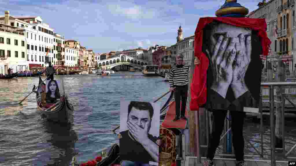 Gondoliers show pictures of models representing the three stages of silence: &quot;I don&#39;t see, I don&#39;t hear, I don&#39;t speak&quot;, during an event to mark the International Day of Violence against Women, on Venice&#39;s Grand Canal, near the Rialto Bridge.