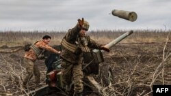 A Ukrainian serviceman of an artillery unit throws an empty shell as they fire towards Russian positions on the outskirts of Bakhmut, eastern Ukraine, Dec. 30, 2022. 