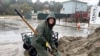 Resident Laurie Morse, 59, shovels wet sand into bags in the pouring rain, a last ditch effort to keep a rising creek out of her garage in the town of Rio Del Mar in Aptos, Calif., Jan. 11, 2023. 